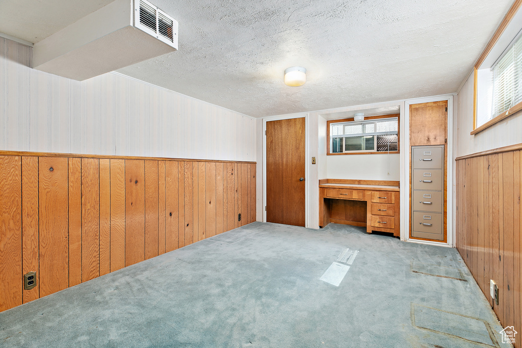 Unfurnished bedroom with wood walls, a wainscoted wall, a textured ceiling, and carpet floors
