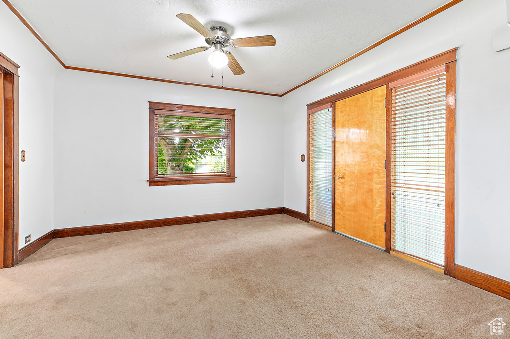 Unfurnished bedroom featuring carpet floors, ornamental molding, baseboards, and a ceiling fan