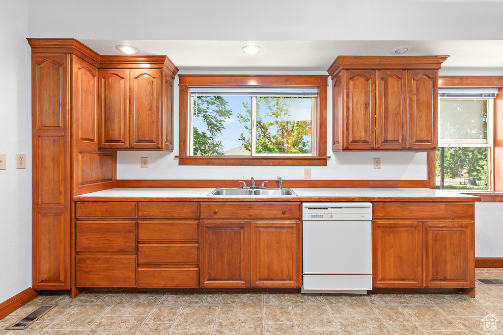 Kitchen featuring dishwasher, a sink, plenty of natural light, brown cabinets, and recessed lighting