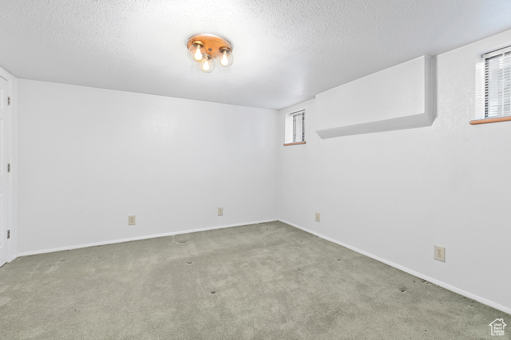 Carpeted empty room featuring a textured ceiling and baseboards