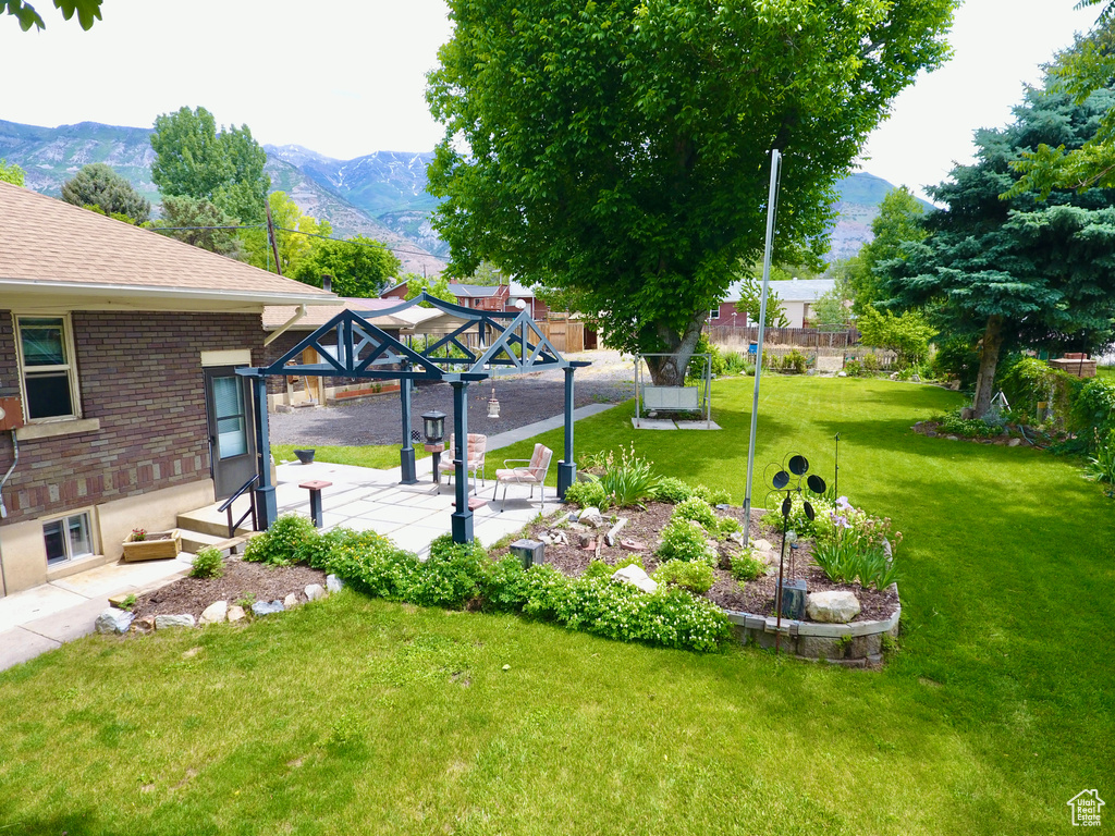 View of grassy yard with a mountain view, a gazebo, and a patio
