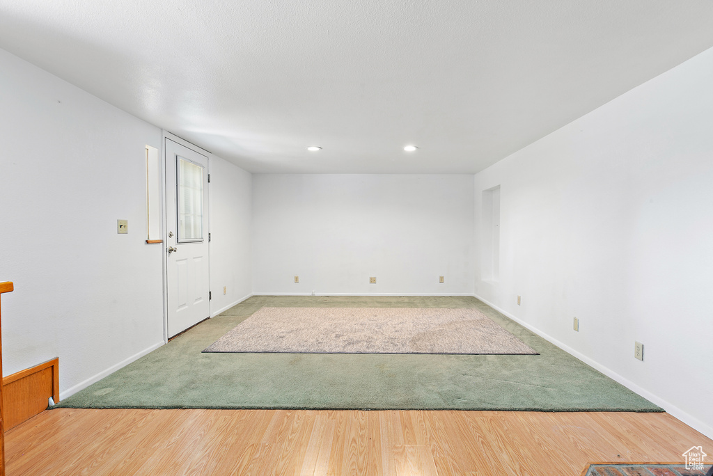 Carpeted spare room featuring wood finished floors, baseboards, and recessed lighting