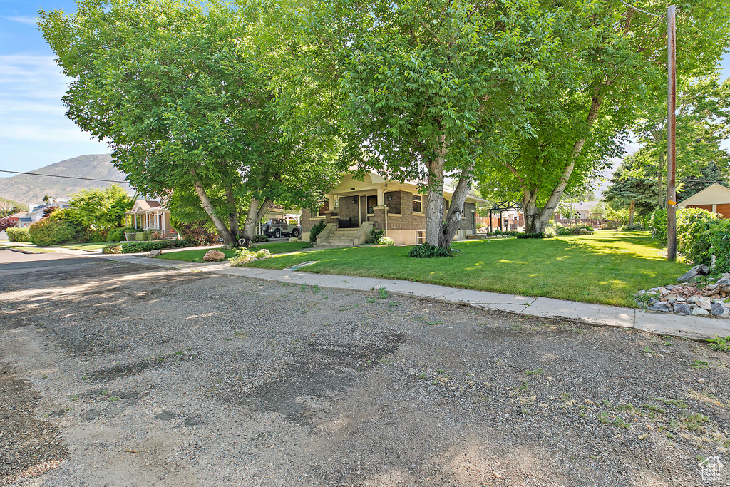 Obstructed view of property featuring a front lawn, a mountain view, and a residential view