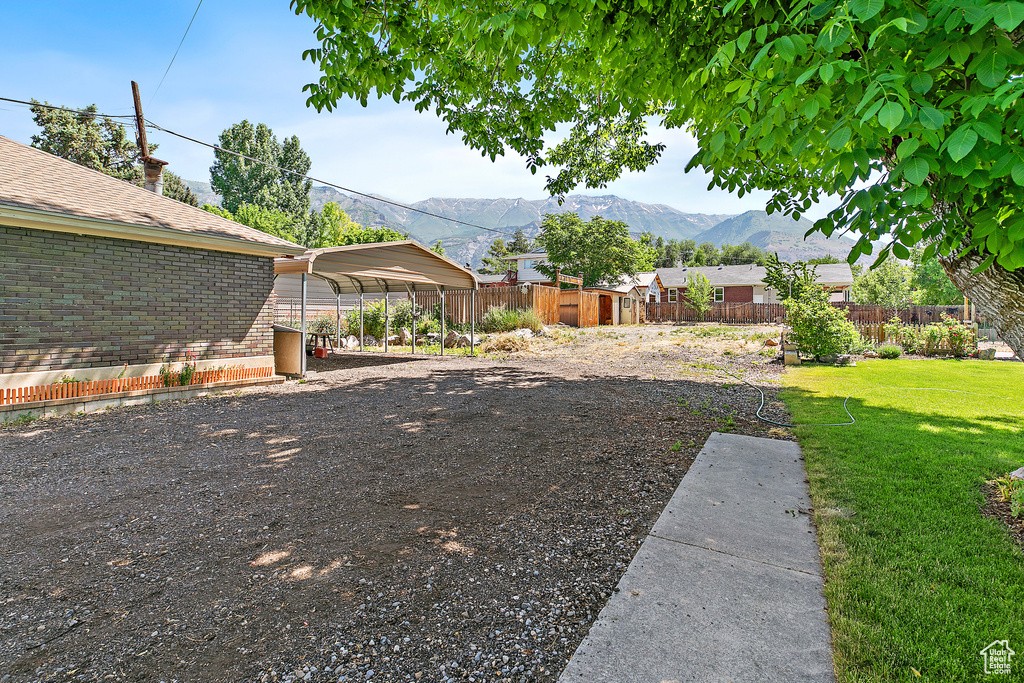 View of yard with a detached carport, a mountain view, and driveway