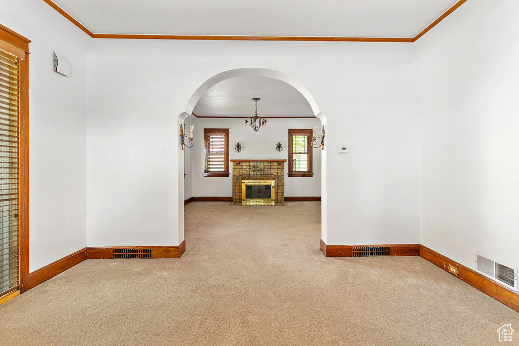 Unfurnished living room with carpet floors, arched walkways, ornamental molding, baseboards, and a chandelier