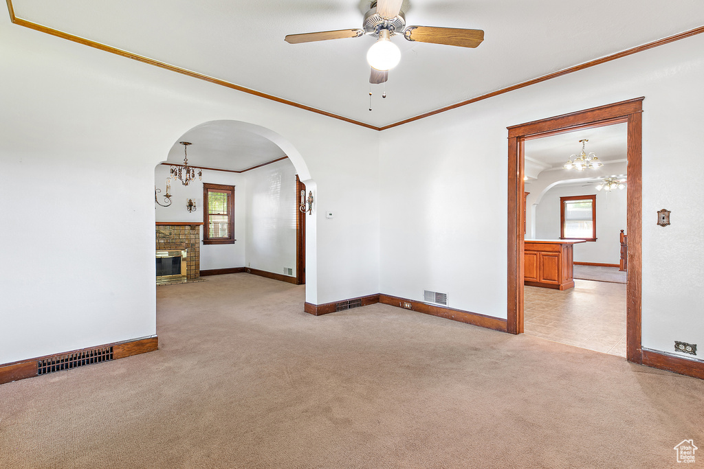 Empty room featuring ornamental molding, light carpet, arched walkways, healthy amount of natural light, and baseboards