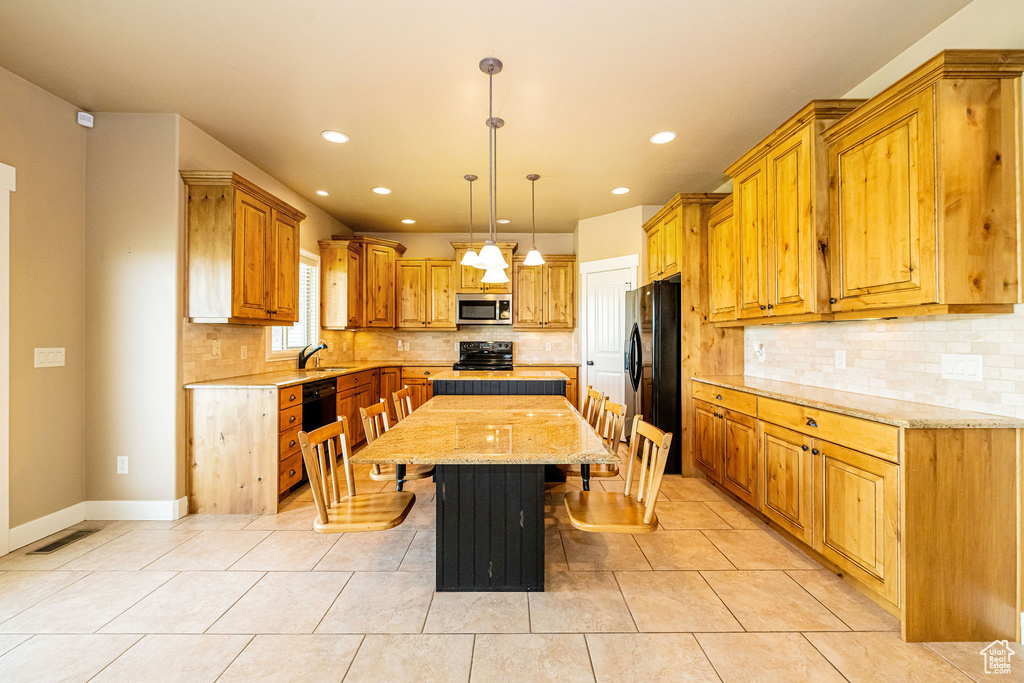 Kitchen featuring black appliances, recessed lighting, a center island, a kitchen breakfast bar, and tasteful backsplash
