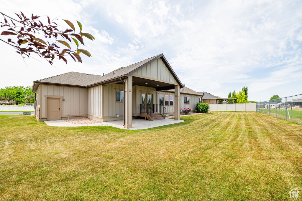 Back of house featuring board and batten siding, a patio, and roof with shingles