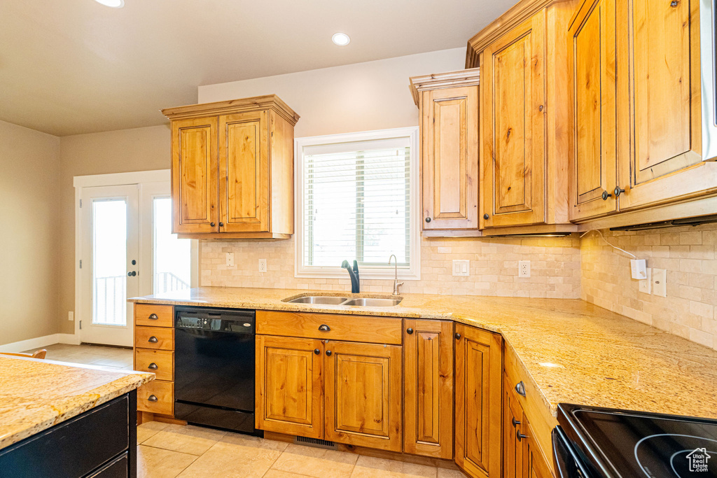 Kitchen featuring black appliances, a sink, backsplash, light stone counters, and light tile patterned floors