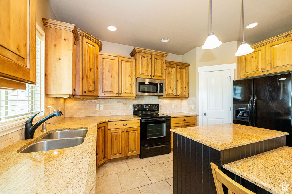 Kitchen featuring black appliances, a sink, light stone countertops, light tile patterned floors, and tasteful backsplash