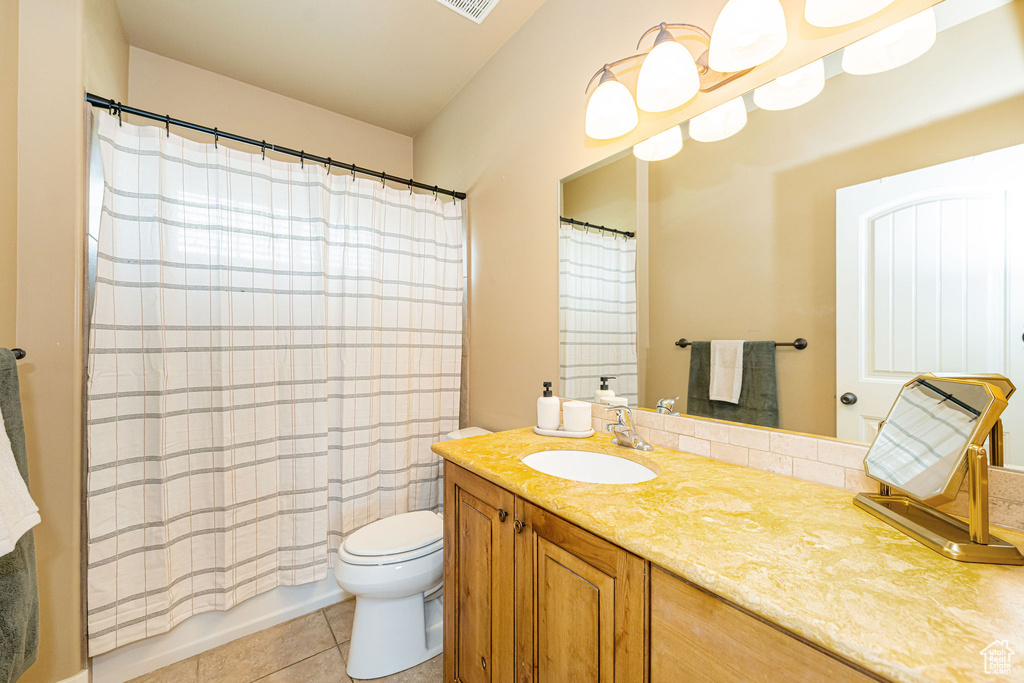 Full bathroom featuring toilet, vanity, tile patterned flooring, and shower / bath combo with shower curtain