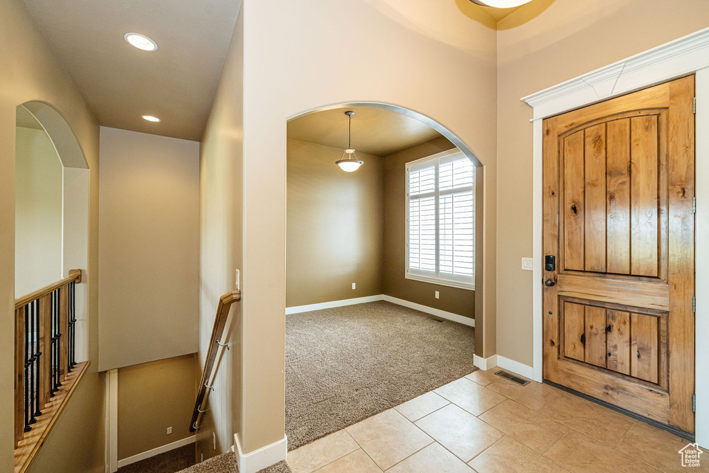 Entrance foyer with light carpet, arched walkways, light tile patterned floors, recessed lighting, and baseboards