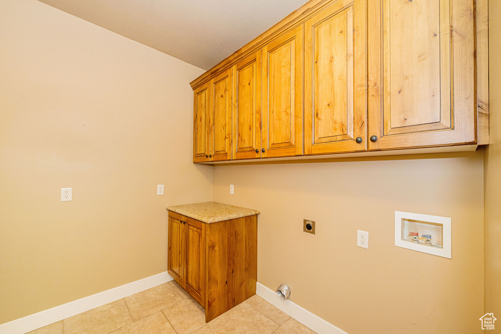 Laundry area with electric dryer hookup, cabinet space, hookup for a washing machine, baseboards, and light tile patterned floors