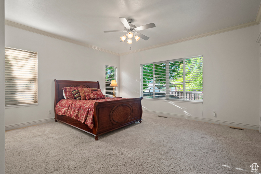 Carpeted bedroom with ornamental molding, baseboards, and ceiling fan