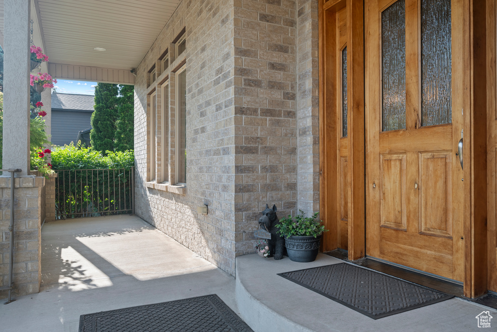Property entrance featuring covered porch and brick siding