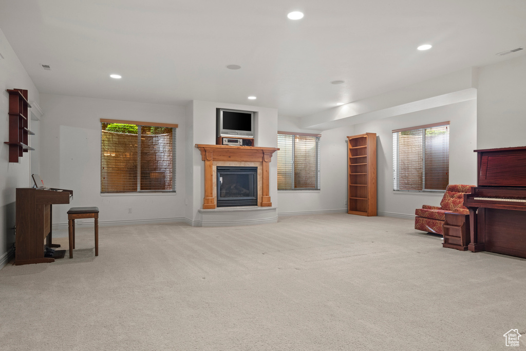 Carpeted living area with a glass covered fireplace, recessed lighting, and baseboards