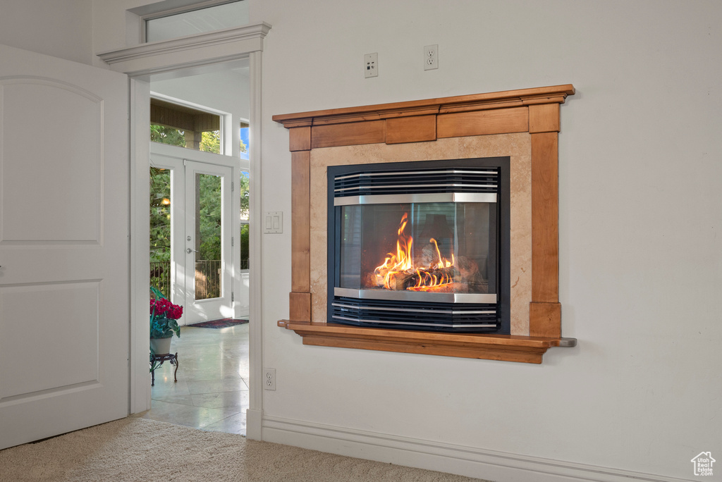 Detailed view of a tiled fireplace, carpet floors, and french doors