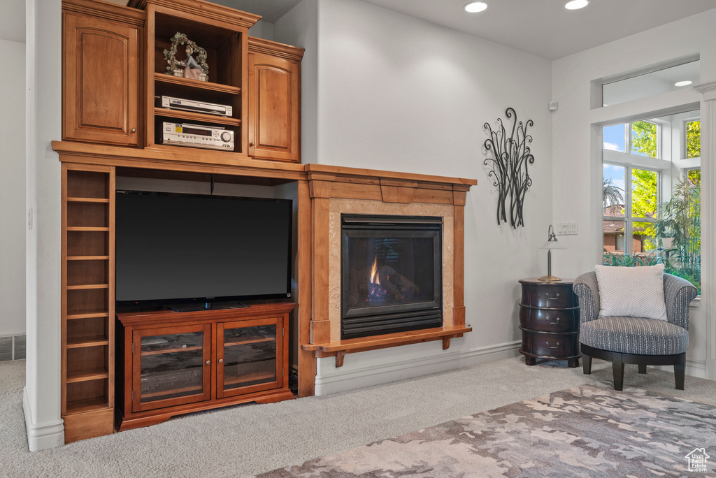 Carpeted living area with recessed lighting, a glass covered fireplace, and baseboards