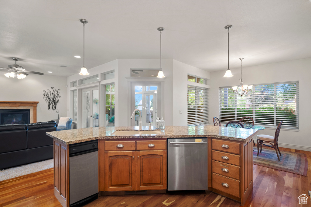 Kitchen with dishwasher, a sink, brown cabinets, and dark wood-style flooring
