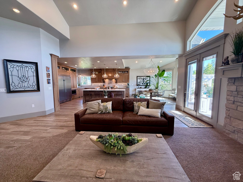 Living area with a towering ceiling, plenty of natural light, recessed lighting, a chandelier, and light wood finished floors