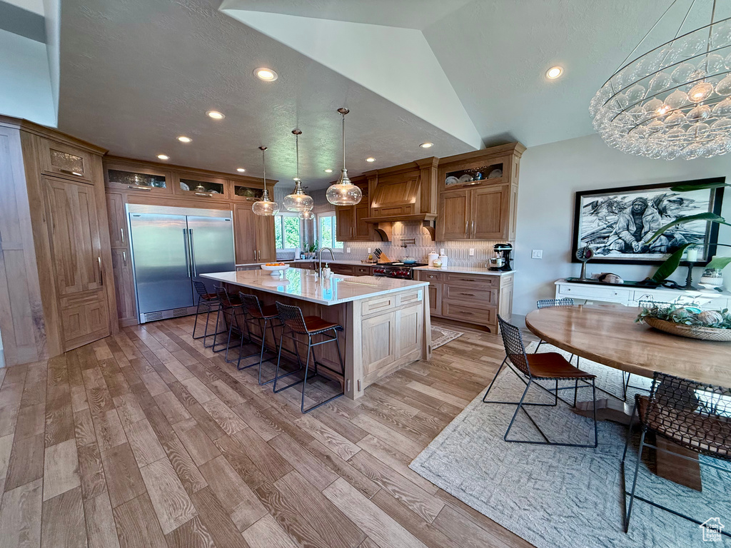 Kitchen with high quality appliances, premium range hood, light countertops, a breakfast bar, and recessed lighting