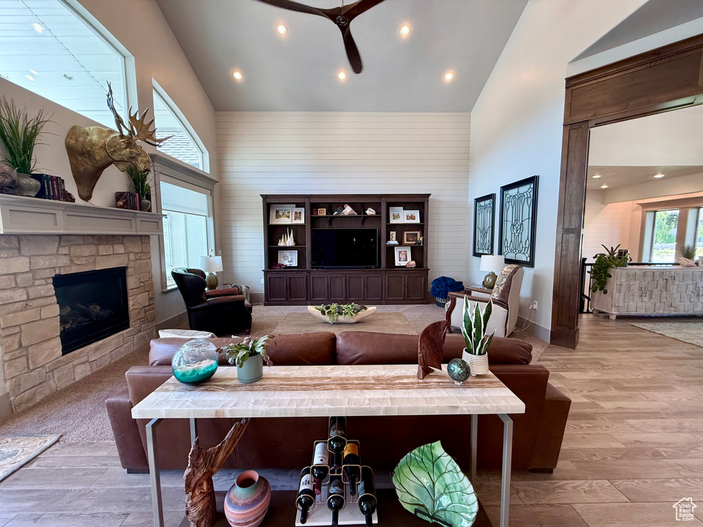 Living area featuring high vaulted ceiling, a fireplace, ceiling fan, recessed lighting, and light wood-style floors