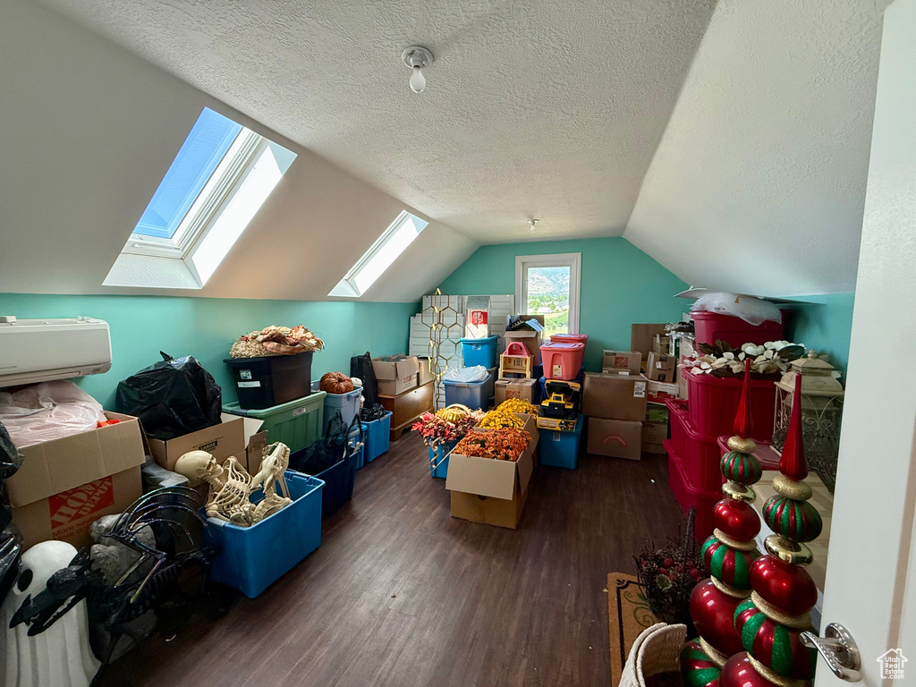 Additional living space with a skylight, wood finished floors, a textured ceiling, and vaulted ceiling