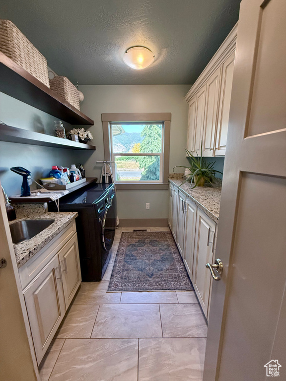 Laundry room with cabinet space, separate washer and dryer, a textured ceiling, and baseboards