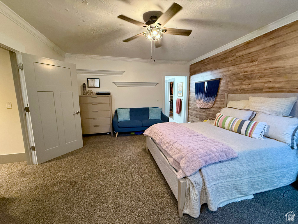 Carpeted bedroom featuring a textured ceiling, wooden walls, a ceiling fan, and crown molding