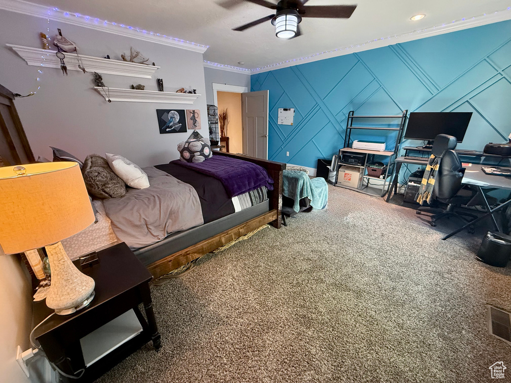 Carpeted bedroom featuring ornamental molding, a decorative wall, ceiling fan, and a desk