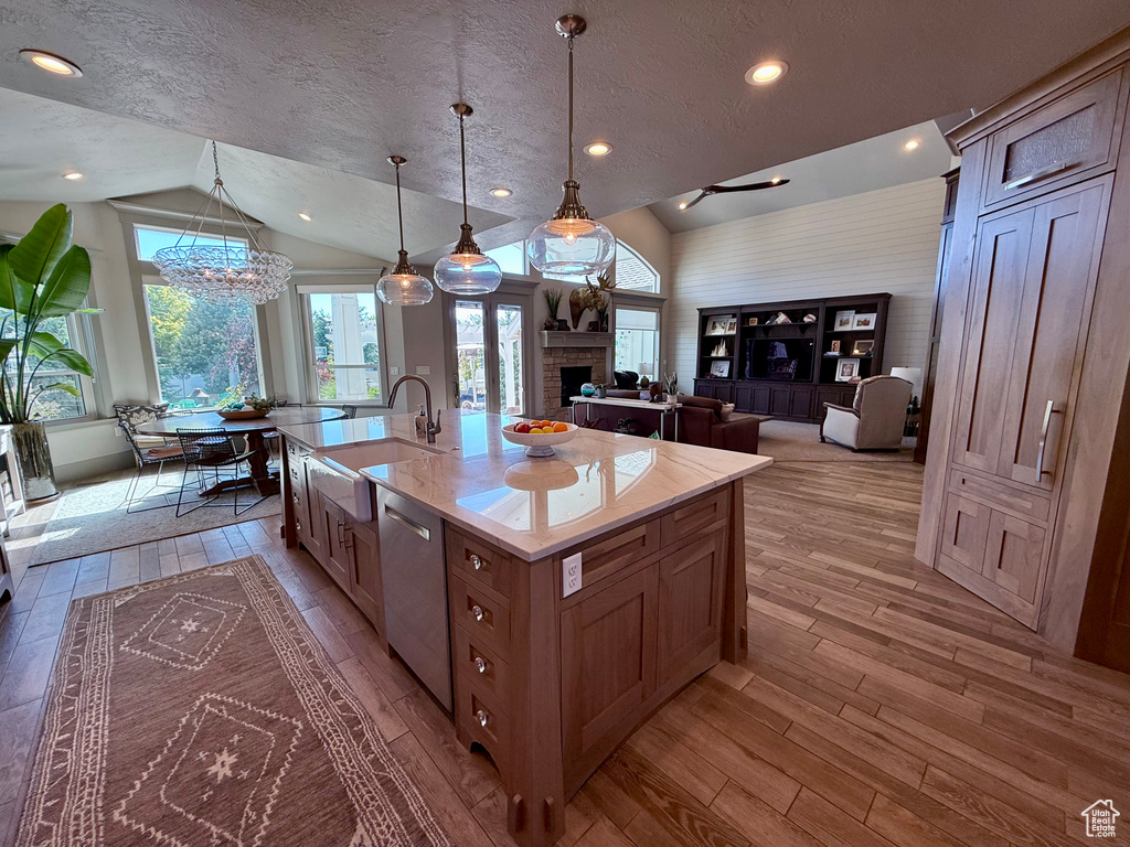 Kitchen featuring lofted ceiling, a sink, dishwasher, light wood finished floors, and a chandelier