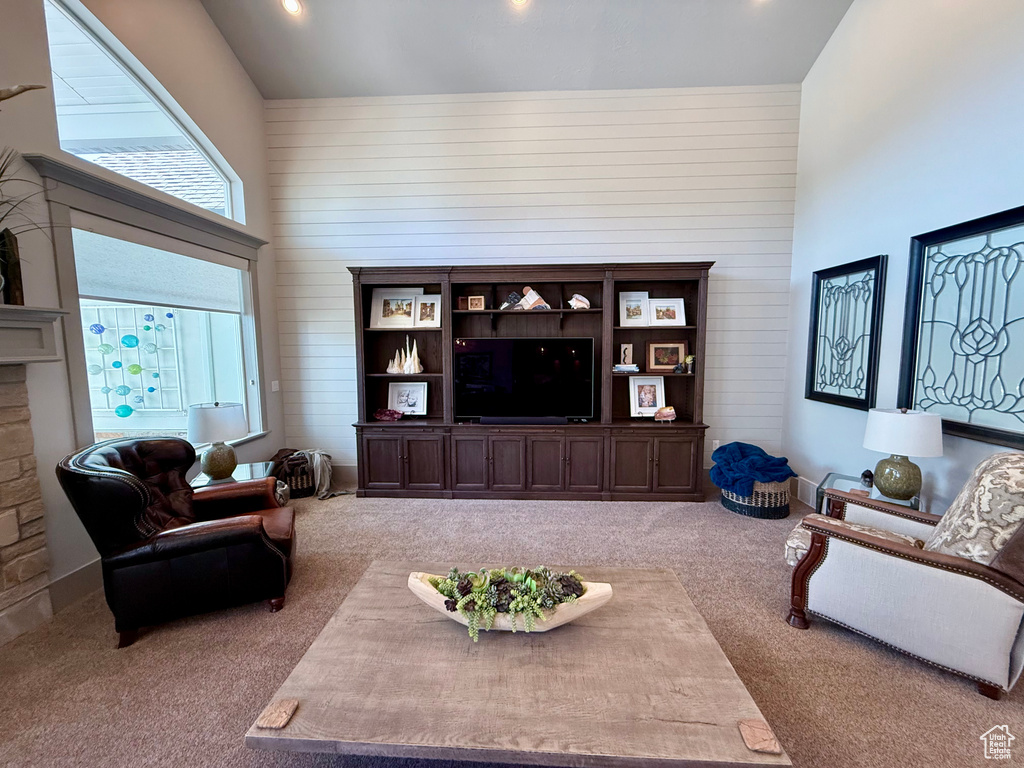 Living area with carpet, high vaulted ceiling, wood walls, and recessed lighting