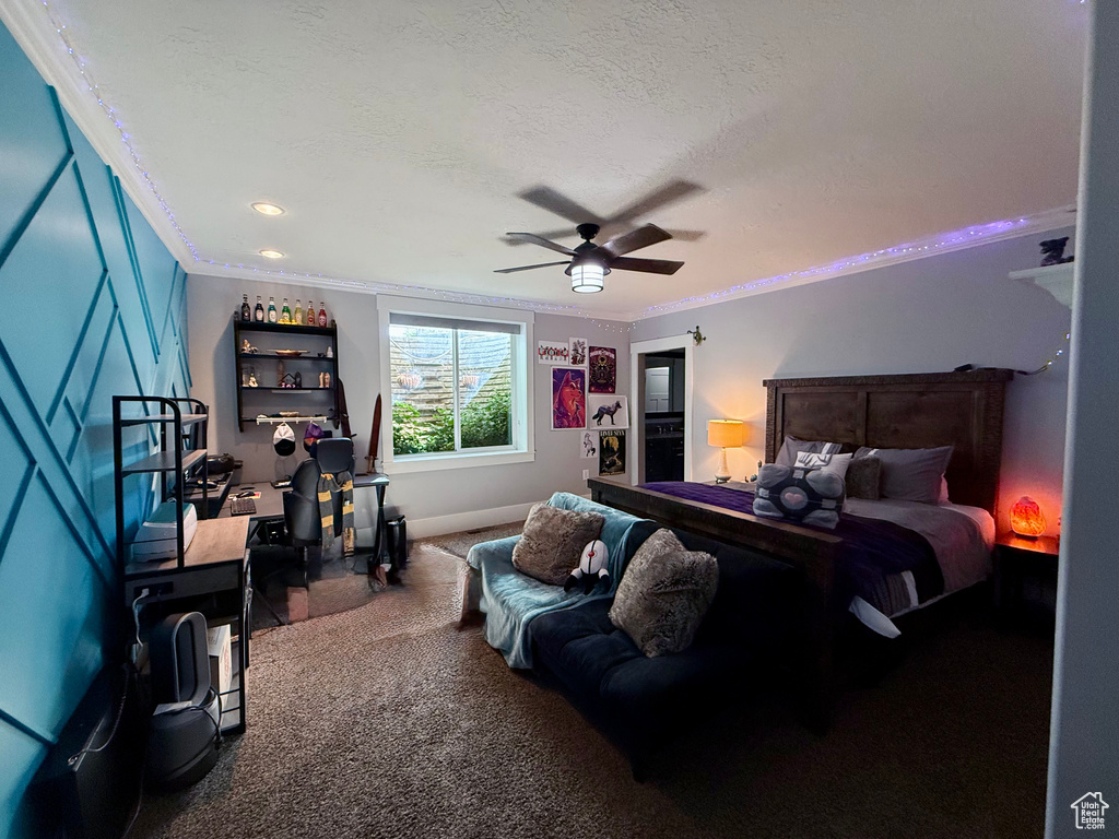 Carpeted bedroom with ornamental molding, a ceiling fan, and a textured ceiling