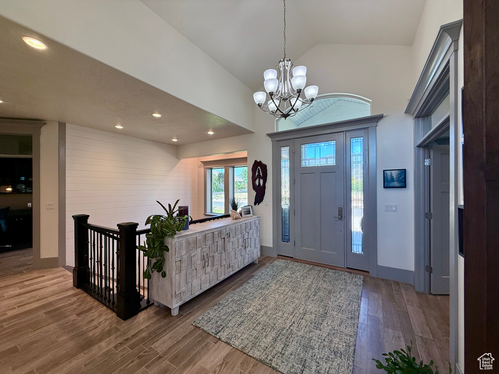 Entrance foyer featuring high vaulted ceiling, wood finished floors, a chandelier, recessed lighting, and baseboards