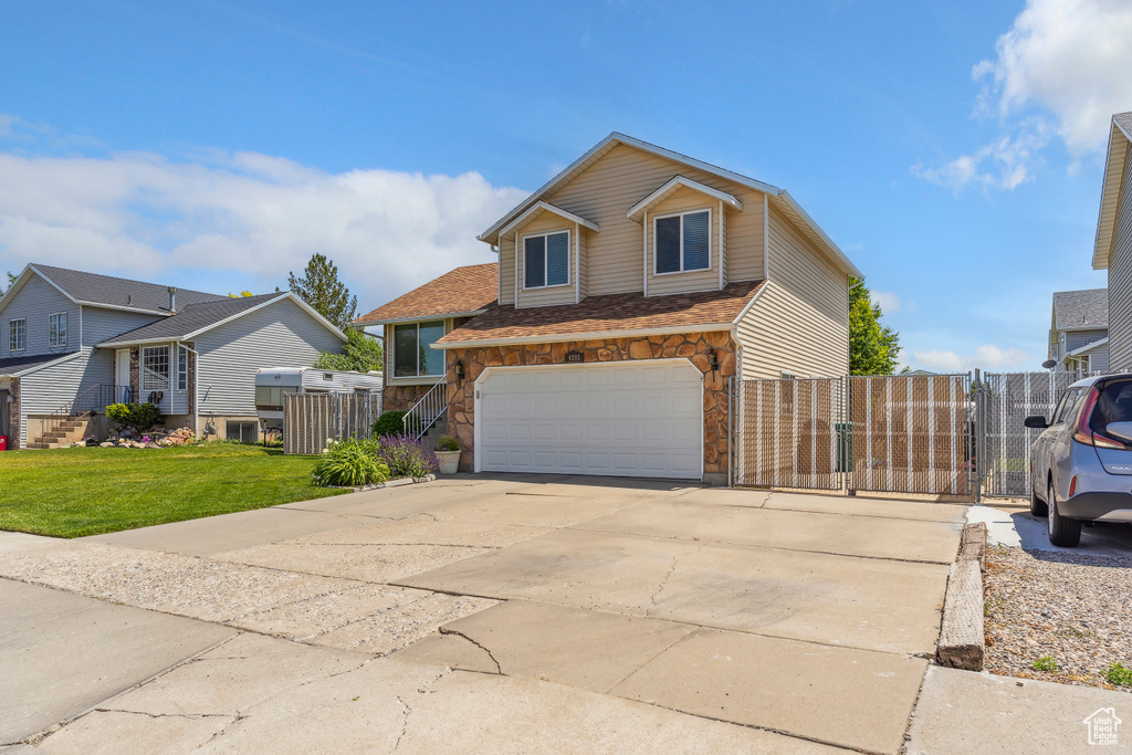 Traditional home featuring a gate, a garage, driveway, stone siding, and a residential view