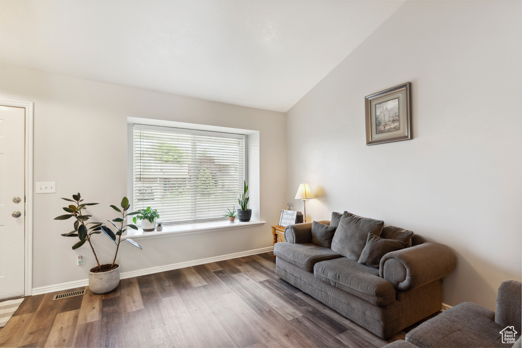 Living area with wood finished floors, lofted ceiling, and baseboards