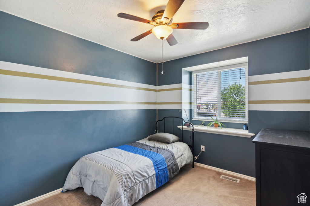 Carpeted bedroom with a textured ceiling, baseboards, and ceiling fan