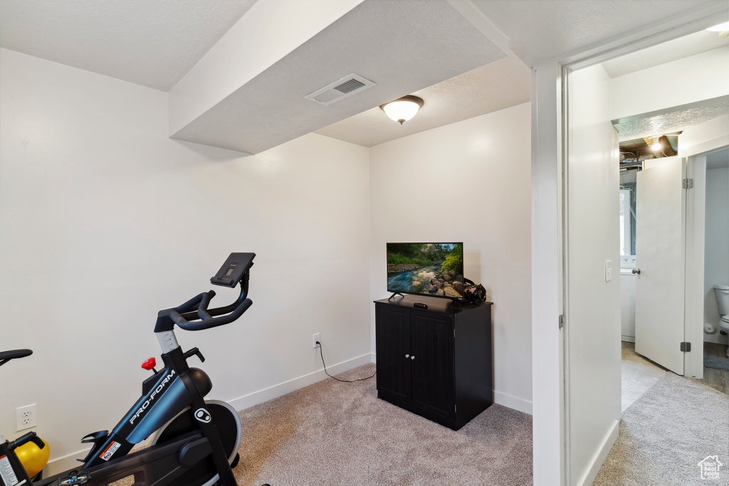 Exercise room with light colored carpet and baseboards