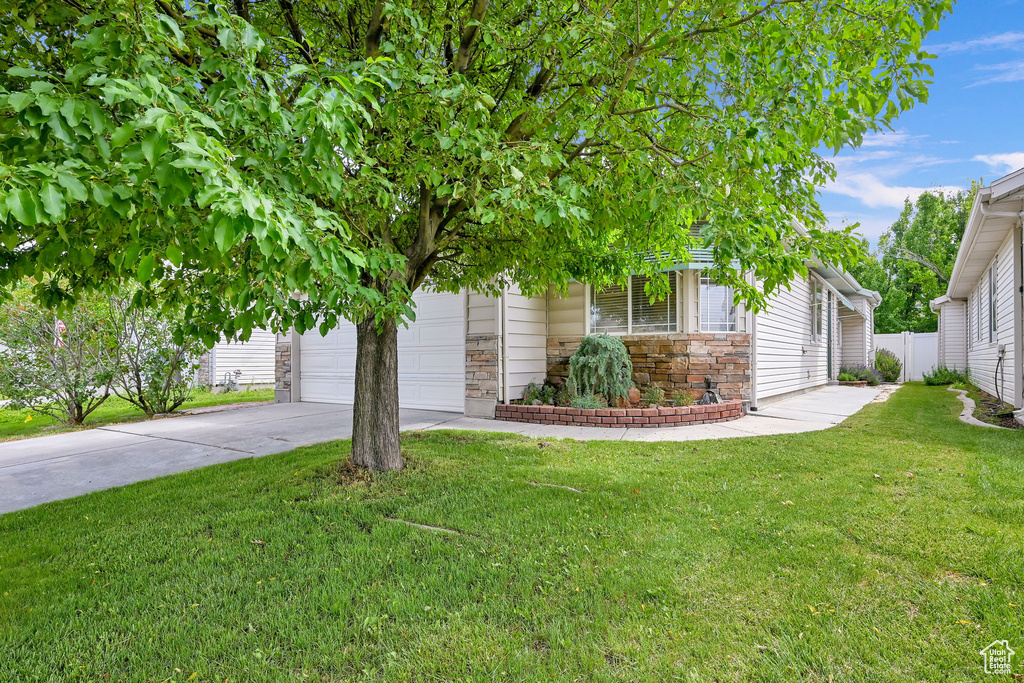 Obstructed view of property with driveway, stone siding, and a garage