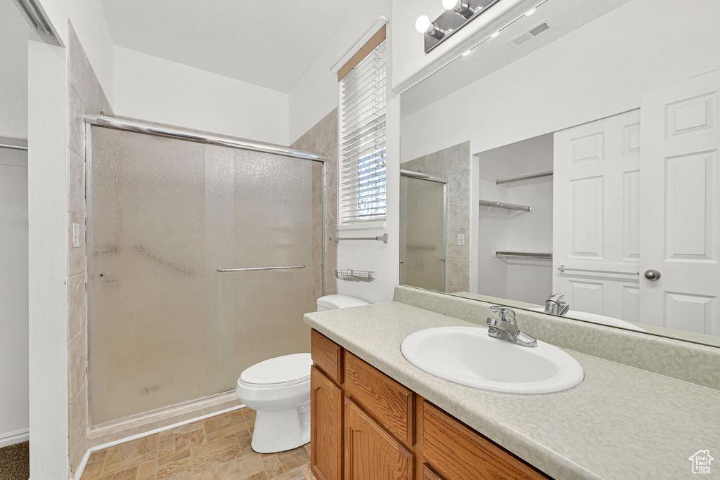 Full bathroom with a shower stall, vanity, toilet, and stone finish floors