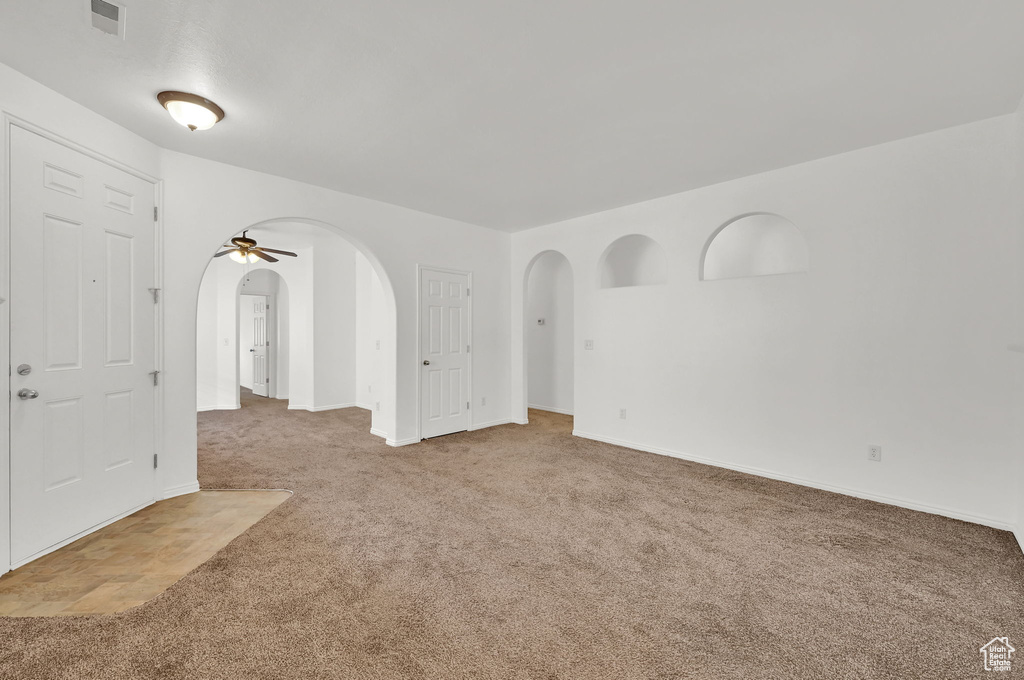 Carpeted spare room featuring arched walkways and baseboards