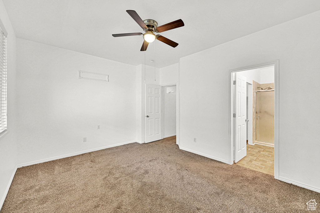 Unfurnished bedroom featuring carpet, baseboards, ensuite bath, and ceiling fan