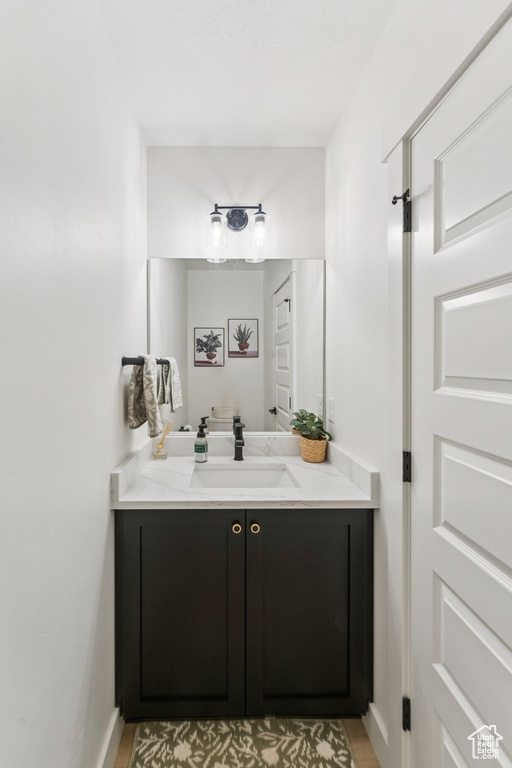 Bathroom with vanity, baseboards, and wood finished floors