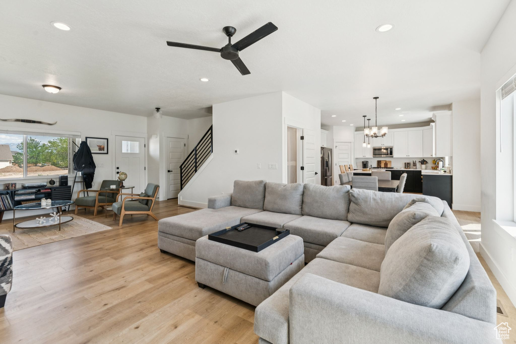 Living area featuring a chandelier, stairway, a ceiling fan, recessed lighting, and light wood-style flooring