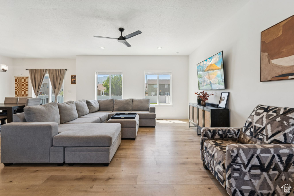 Living area featuring light wood finished floors, ceiling fan, a chandelier, and recessed lighting