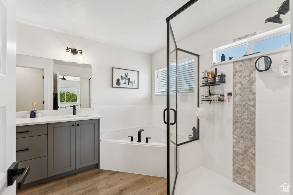 Bathroom with vanity, a bath, a shower stall, and wood finished floors