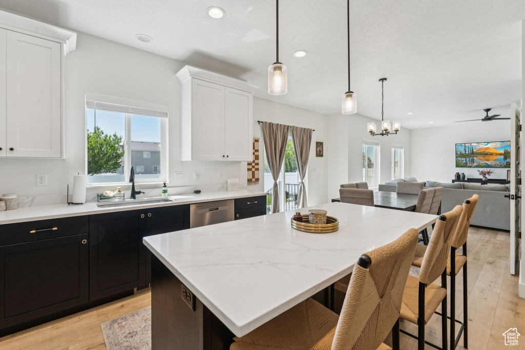 Kitchen with a sink, light wood-style flooring, white cabinets, a center island, and recessed lighting
