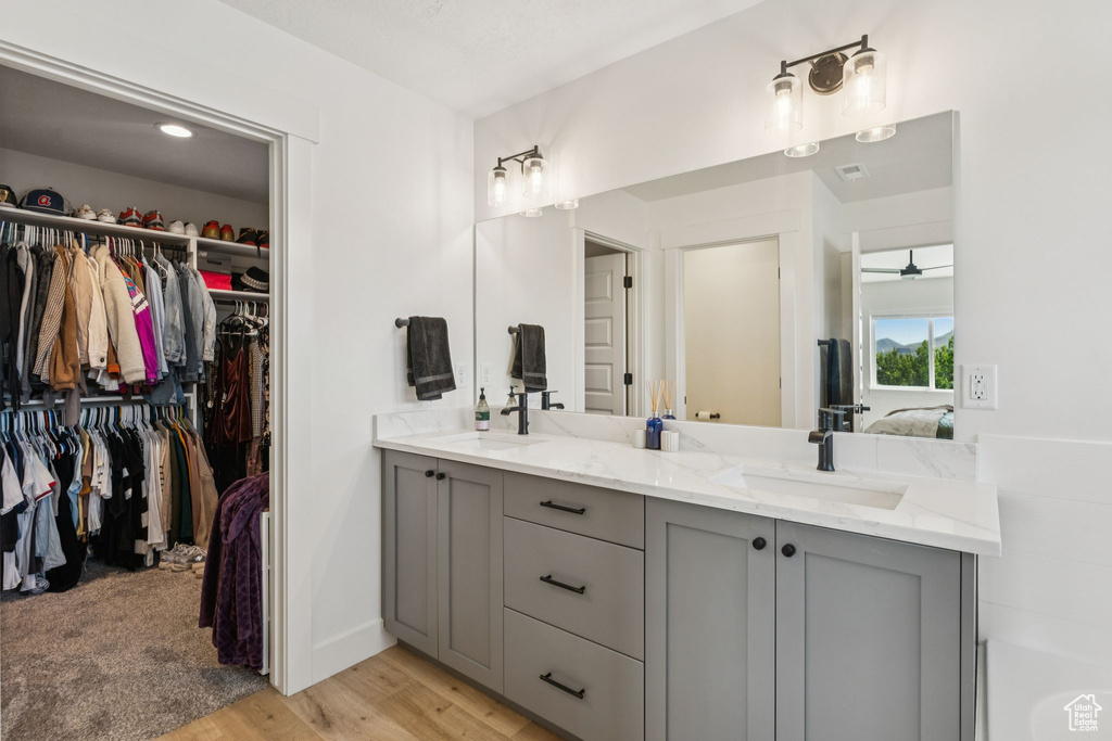 Full bathroom featuring double vanity, wood finished floors, and a walk in closet