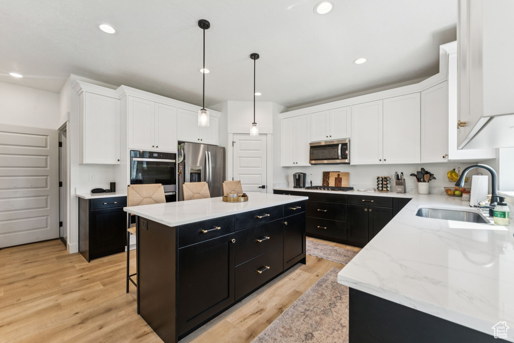 Kitchen with dark cabinets, stainless steel appliances, a kitchen island, white cabinetry, and recessed lighting