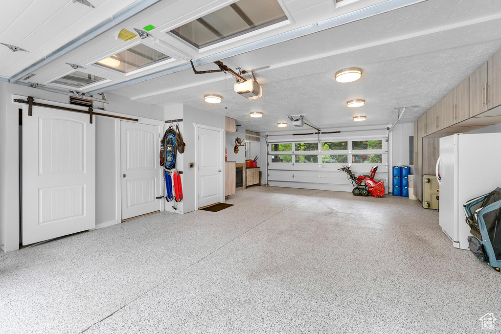 Garage featuring freestanding refrigerator and a garage door opener